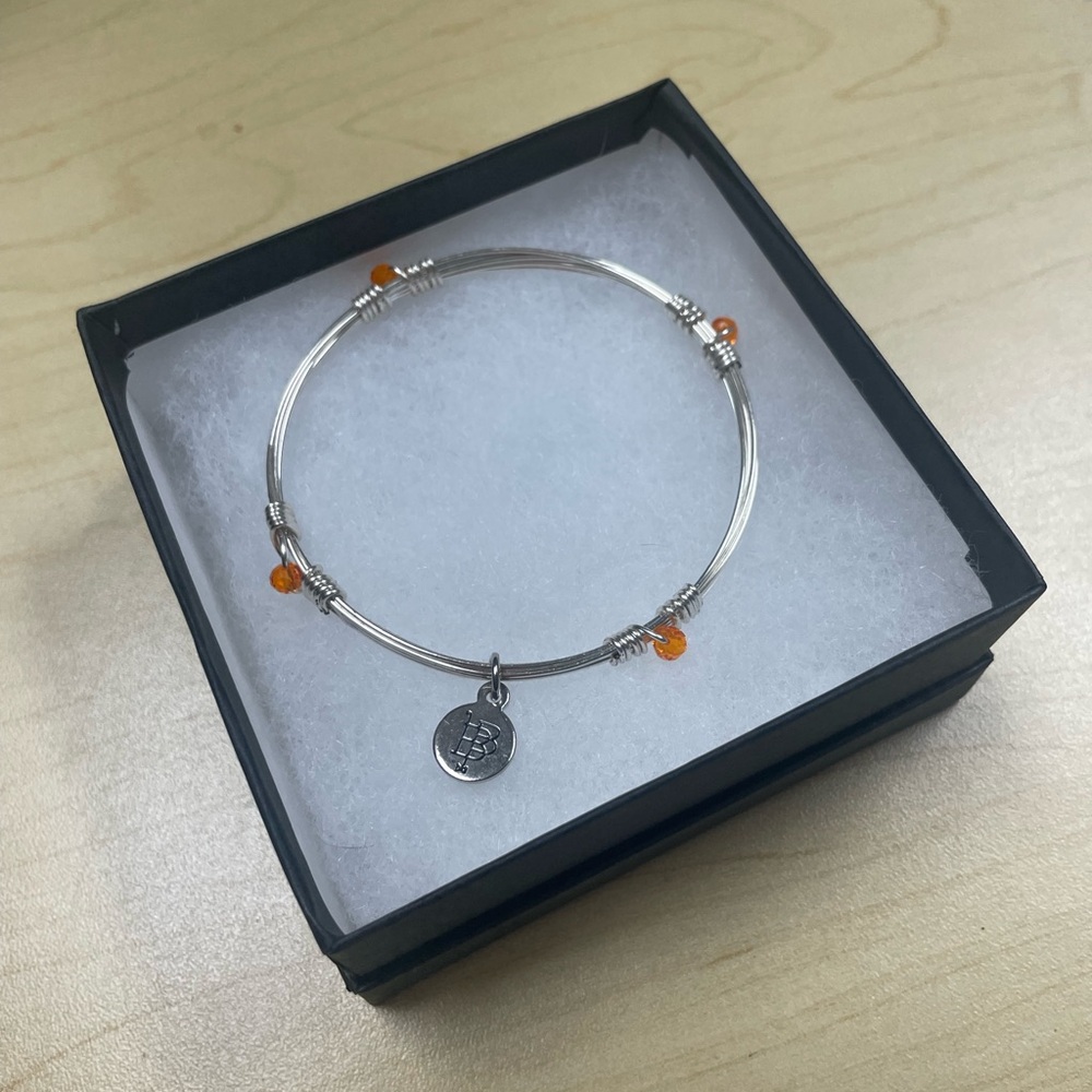 Bourbon and Boweties standard size silver bangle with orange bead accents